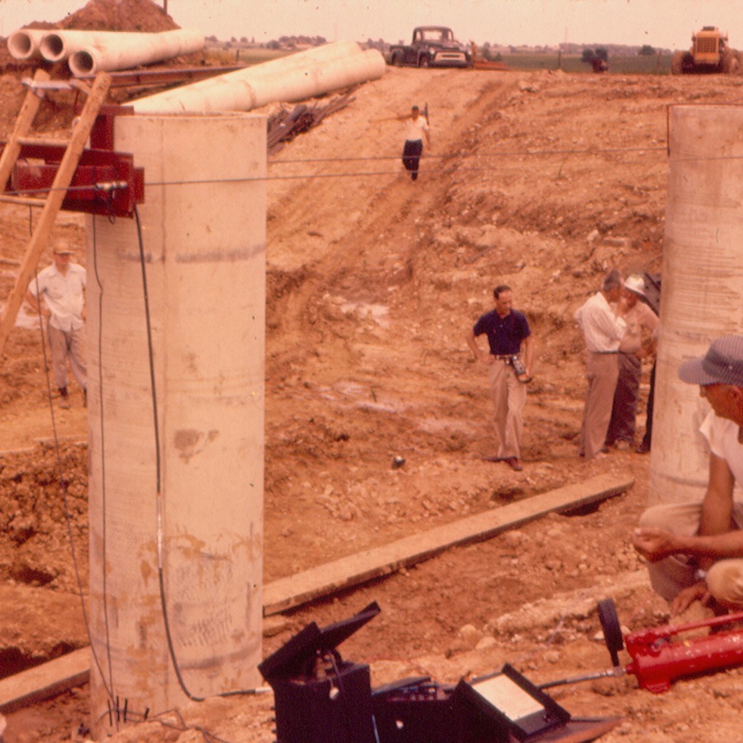 Jack Janney, dark shirt, observes construction of the Beverly Road Bridge, built circa 1957 with precast, prestressed concrete girders by the Illinois Tollroad Authority.